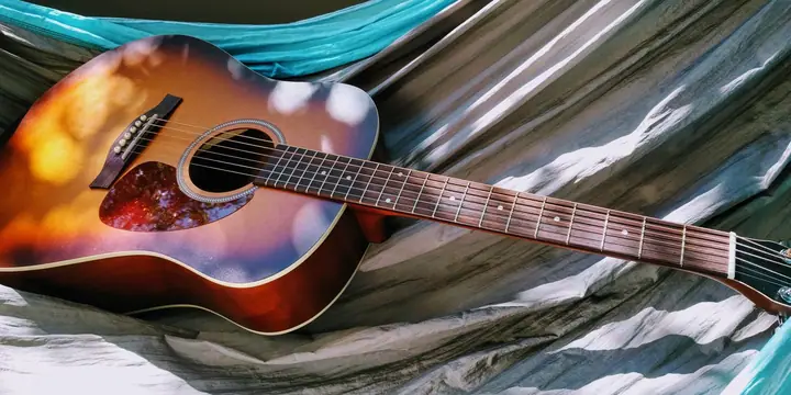 Akustikgitarre mit Sunburst-Lackierung liegt auf einem zerknitterten Stoff
